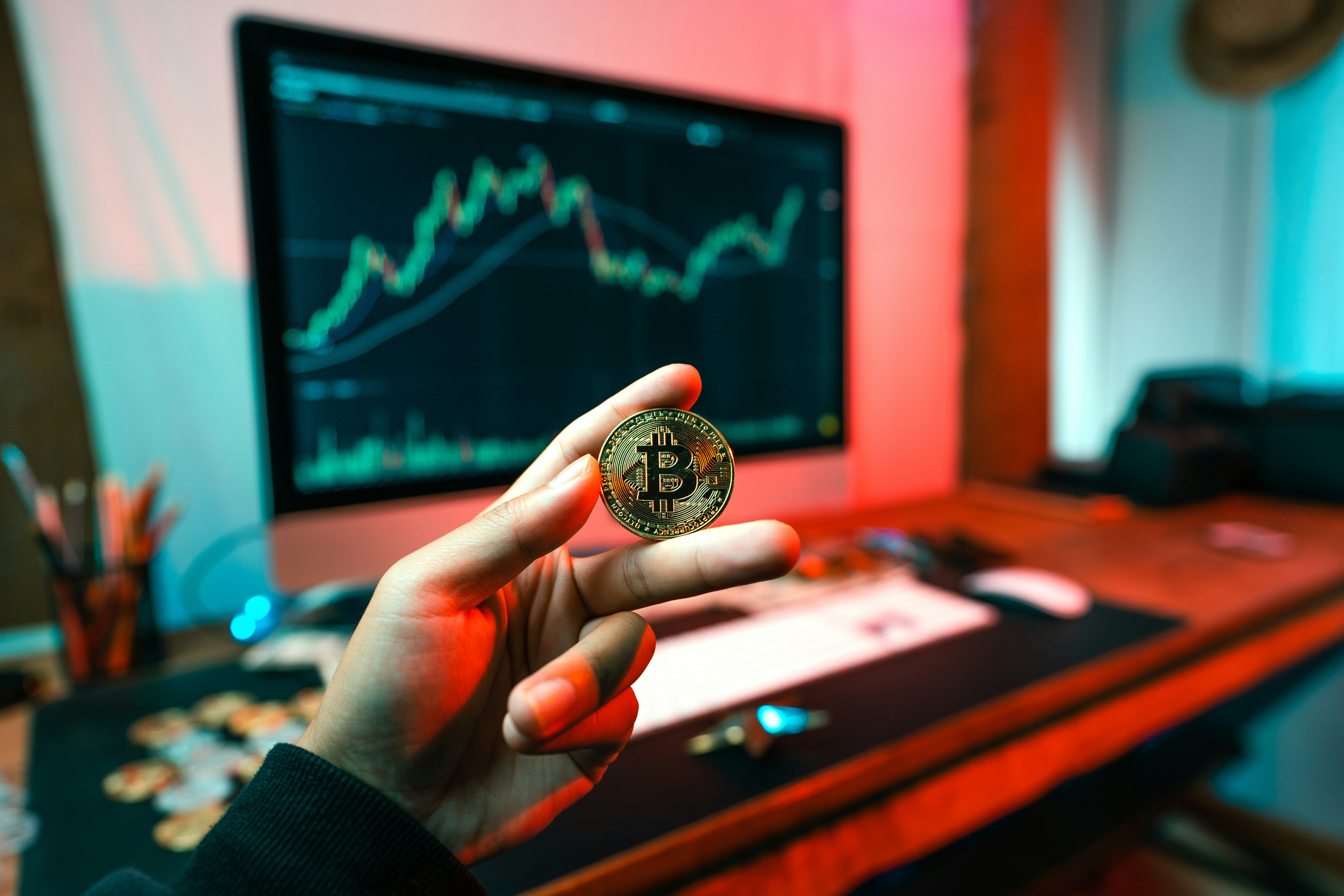A real bit-coin in front of a monitor with charts