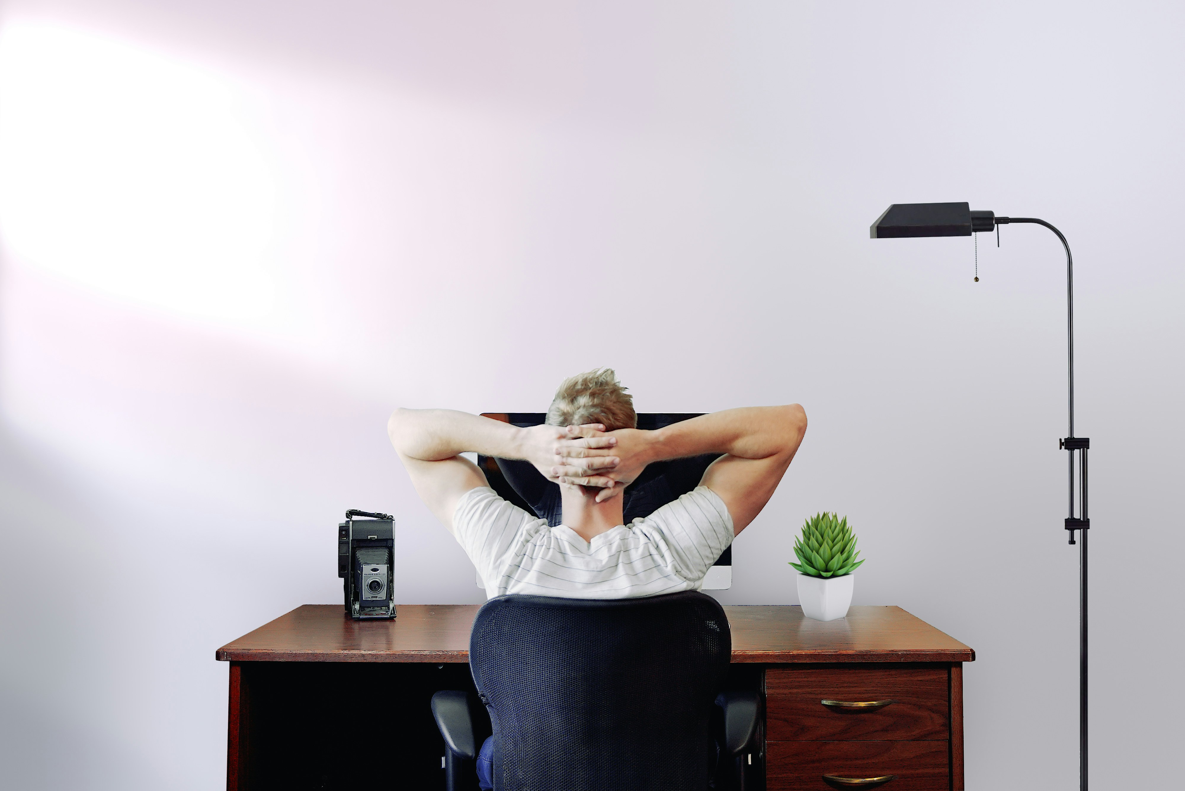 A guy thinking on his chair infront of his desk